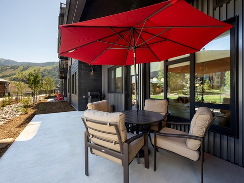 Relax on your private patio with mountain views, comfortable seating, and a bright red umbrella shading your outdoor dining table—perfect for morning coffee or evening gatherings.