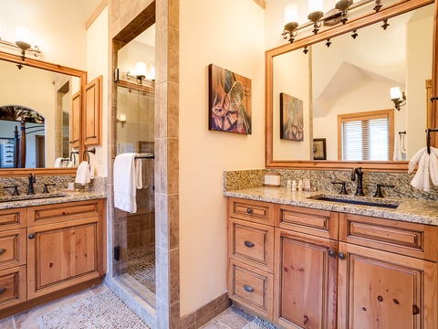 Freshen up in your elegant ensuite with dual vanities, granite counters, and a walk-in shower framed by warm rustic cabinetry and thoughtful lighting.