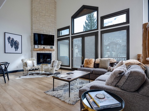 Unwind in your spacious living room with soaring ceilings, a warm stone fireplace, and plush seating designed for ultimate comfort. Natural light floods through oversized windows.