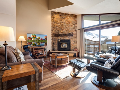 Unwind in your inviting living room with soaring ceilings, a cozy stone fireplace, and sweeping mountain views through expansive windows. Your perfect retreat after a day of adventure.