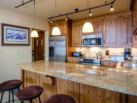 You'll love preparing meals in this fully equipped kitchen, featuring warm wood cabinetry, granite countertops, stainless steel appliances, and stylish pendant lighting that creates a cozy atmosphere.