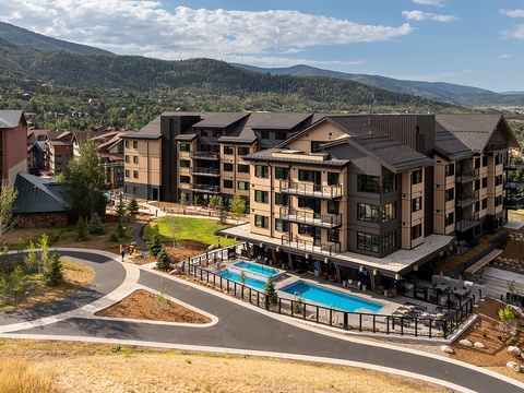 A contemporary mountain property featuring alpine architecture and scenic placement amid forested slopes. The community features modern multi-story residences, outdoor pool facilities, and convenient access to surrounding recreational terrain.