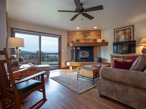 Relax in your cozy living room with mountain views through sliding doors, a warm fireplace, and comfortable seating where you can unwind after a day of adventure.