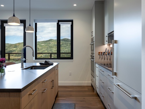 Picture yourself preparing meals in this bright, modern kitchen with sleek countertops and expansive mountain views right through your window—your perfect culinary retreat.