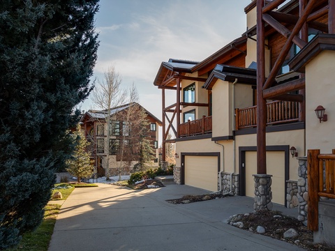 Mountain-style architecture with timber beams and stone accents set in a tranquil, tree-lined neighborhood, offering a peaceful alpine retreat.