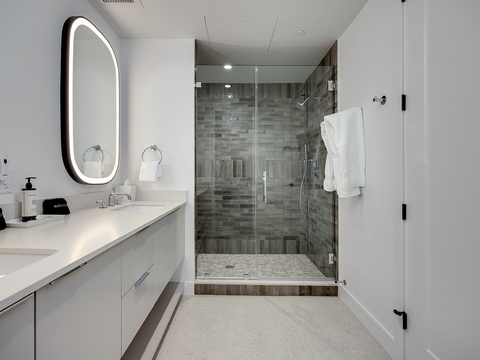 Step into your spa-like bathroom where a gleaming walk-in shower with modern subway tiles and a backlit mirror invite you to unwind after exploring the area.