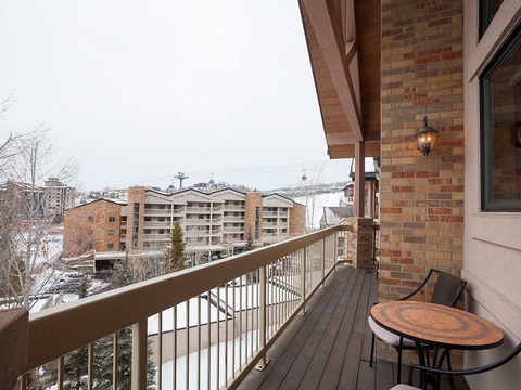 Private balcony overlooking snowy mountain village with ski slopes, perfect for morning coffee with scenic winter views.