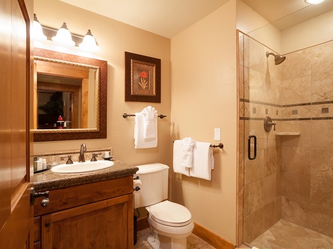 Step into your private bathroom featuring warm travertine tile, a spacious walk-in shower, and crisp white towels awaiting your arrival.