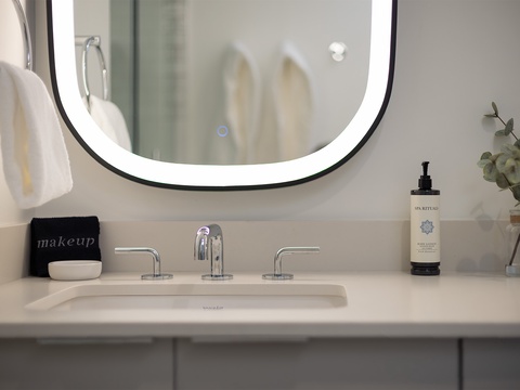 Your pristine bathroom vanity awaits with soft towels, luxury toiletries, and a sleek lighted mirror—everything ready for a refreshing start to your day.