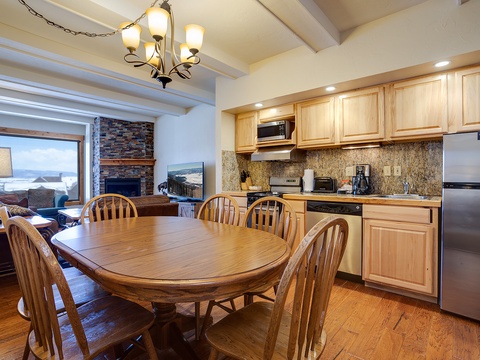 Gather around the warm wooden table in your fully-equipped kitchen, where a cozy fireplace and mountain views create the perfect backdrop for memorable meals together.