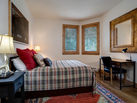 Your cozy bedroom features a plush bed with inviting linens, warm wood accents, and a convenient workspace—perfect for unwinding after exploring the area.