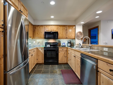 Prepare meals in a spacious, fully-equipped kitchen with stainless steel appliances, warm wood cabinetry, and granite countertops, perfect for your culinary adventures.