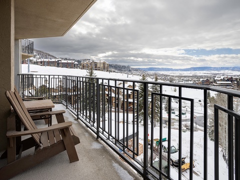 A covered balcony offers sweeping views of snow-dusted mountains, evergreen trees, and the valley below—a peaceful spot to take in the scenic winter landscape surrounding the property.