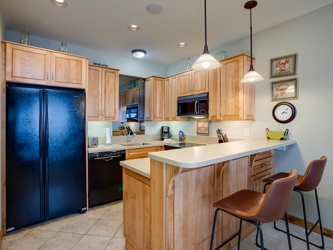 Your fully equipped kitchen invites you to whip up delicious meals with modern appliances, warm wood cabinetry, and a breakfast bar perfect for casual dining or morning coffee.