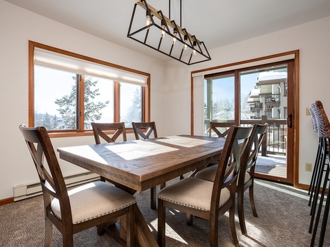 Gather around this inviting dining table, where natural light pours in through large windows and opens to a balcony with stunning mountain views—your perfect spot for memorable meals together.