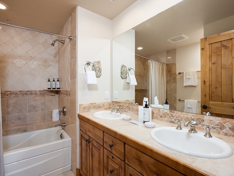 Freshen up in your spacious bathroom with dual sinks, a tiled tub-shower combo, and rustic wood cabinetry that adds warmth to your daily routine.