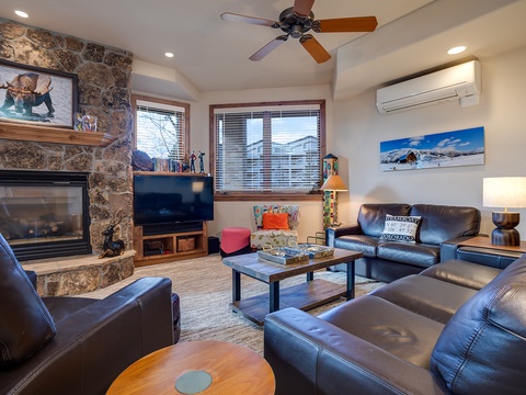 Unwind in your inviting living room with plush leather seating, a crackling stone fireplace, and mountain views framed by large windows—your perfect retreat after a day of adventure.