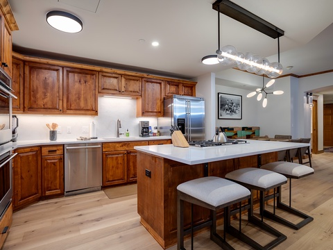 Gather around the spacious island and enjoy cooking in a fully equipped kitchen with stainless steel appliances, ample counter space, and stylish modern lighting overhead.