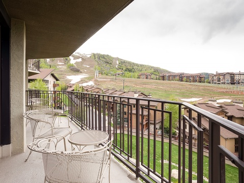 Balcony framed by ski slopes and mountain scenery showcasing the off-season landscape and surrounding resort buildings in a mountain community setting.