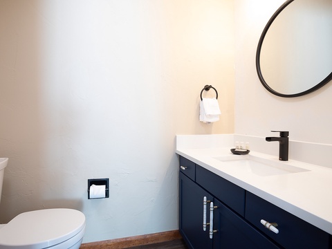 Your private bathroom features a sleek vanity with modern fixtures, fresh towels, and a stylish round mirror to start your day feeling refreshed.