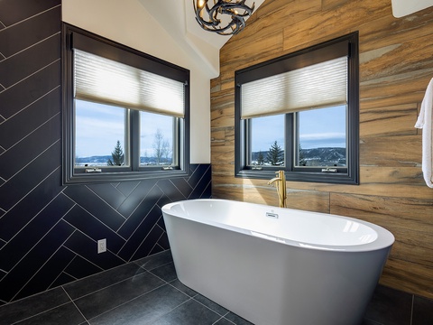 Sink into this elegant freestanding tub and let your stress dissolve as you gaze out at scenic mountain views framed by warm wood accents and sleek herringbone tile.