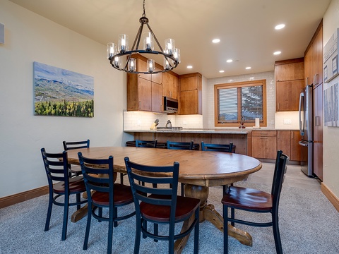 Picture yourself gathering around this spacious dining table under warm chandelier light, ready to share meals and laughter. The open kitchen invites effortless entertaining while mountain views inspire your stay.