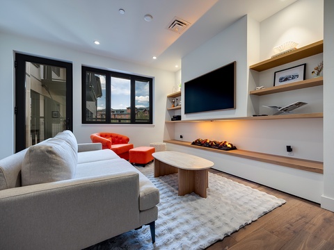 Unwind in your chic living room with cozy seating, modern fireplace, and open shelving for personal touches. Large windows frame mountain vistas, while warm lighting and natural textures invite relaxation.