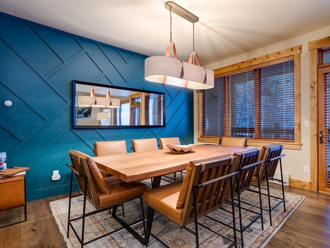Gather around this stunning live-edge table beneath modern pendant lighting. The bold blue accent wall and warm leather chairs create an inviting space for meals and conversations you'll cherish.