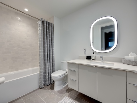 Your pristine bathroom features a sleek vanity with ample storage, a backlit mirror, and a relaxing tub-shower combo—everything you need to unwind after a day of exploring.
