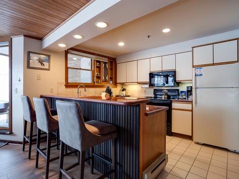 Your fully equipped kitchen features modern appliances, warm wood accents, and a stylish breakfast bar—perfect for preparing meals and gathering with family or friends during your stay.