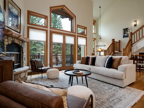 Unwind in your bright and spacious living room, where soaring ceilings and floor-to-ceiling windows frame serene forest views. Sink into plush seating by the stone fireplace and let natural light fill your mountain retreat.