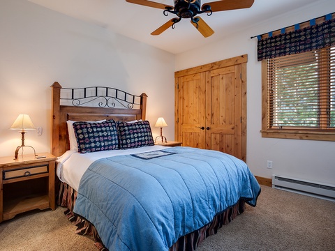 Drift off in this cozy bedroom where rustic charm meets comfort. Your plush bed awaits beneath a gentle ceiling fan, with soft lighting and warm wood tones creating the perfect retreat after a day of adventure.