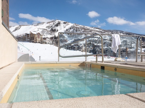 A rooftop pool overlooks a snow-covered mountain resort, offering skiers and outdoor enthusiasts a relaxing alpine retreat after hitting the slopes.