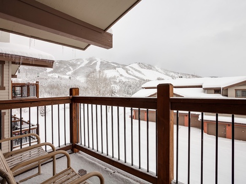 Snow-draped ski slopes frame the horizon beyond the balcony, offering a peaceful alpine backdrop and scenic views of the surrounding mountain resort area.