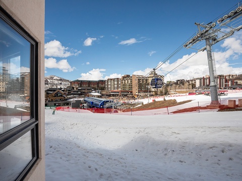 Ski resort village base featuring gondola access, mountain slopes, and surrounding lodges under clear winter skies—defining the property's premier alpine location.