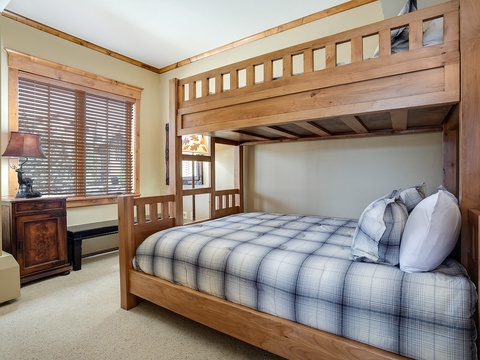Your family can spread out comfortably in this cozy bedroom featuring a sturdy wooden bunk bed with plush plaid bedding, warm lighting, and plenty of space for everyone to relax after a day of adventure.