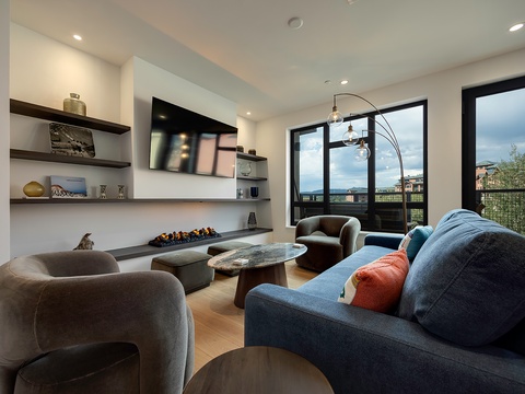 Sink into plush seating and let the day melt away in your elegant living space, where modern design meets natural light through floor-to-ceiling windows overlooking the surrounding area.