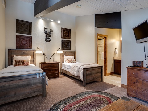 Rustic twin beds with handcrafted wood frames welcome you home after mountain adventures. Warm lighting and charming Western décor create your cozy retreat, complete with an en-suite bathroom.