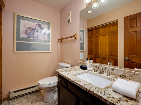 Your private bathroom features a granite vanity, under-mount sink, and plush towels ready for your arrival. Soft lighting and warm wood cabinetry create a spa-like retreat.