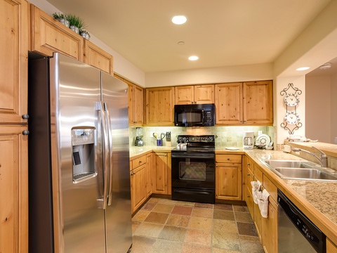 You'll love preparing meals in this bright, fully-equipped kitchen with modern stainless steel appliances, warm wood cabinetry, and plenty of counter space for your culinary creations.