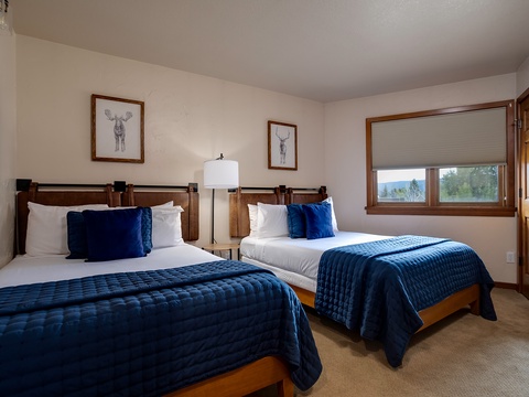 Sink into plush bedding after a day exploring the mountains. Two comfortable beds, soft lighting, and serene artwork create a restful haven where you'll wake refreshed and ready for adventure.