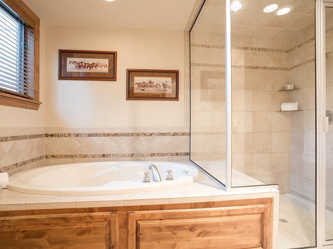 Unwind in your elegant bathroom featuring a deep soaking tub and walk-in shower with beautiful tiled accents, perfect for relaxing after a day of adventure.
