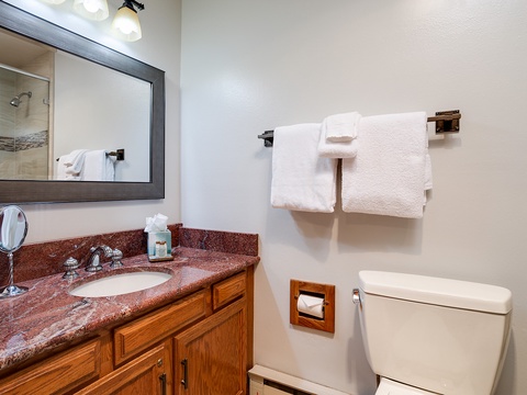 Step into your private bathroom with fresh towels waiting, polished granite vanity, and a relaxing shower just beyond the mirror.