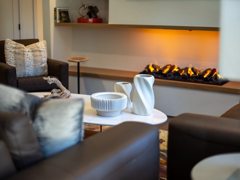 Sink into plush seating as the ambient glow of the fireplace warms your evening, creating a cozy retreat perfect for unwinding after exploring the area.