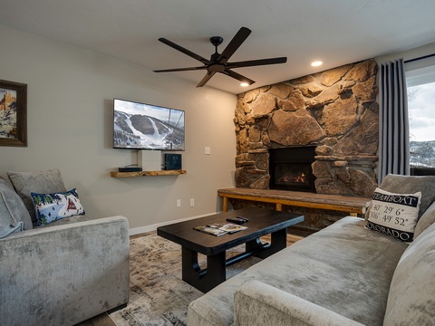 Sink into plush seating and watch the fire glow against the dramatic stone hearth, while mountain views stretch beyond your windows.