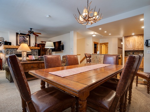 Gather around this rustic dining table under a stunning antler chandelier, perfect for meals and memories with your group in this spacious, warmly-lit retreat.