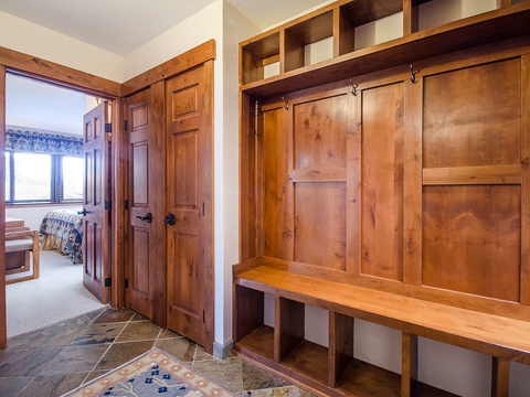 Step into your mountain retreat through this welcoming entryway, where custom wood storage and built-in benches await to organize your gear after a day of adventure.