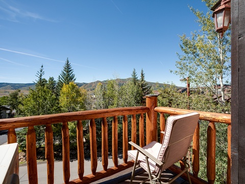 Expansive mountain views frame this private balcony, where evergreens and rolling hills create a peaceful backdrop for relaxing mornings or quiet evenings under open skies.