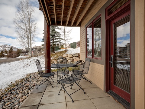 Patio seating tucked beneath an exposed beam overhang with mountain views and winter scenery nearby. The property is nestled in a peaceful neighborhood with easy access to outdoor spaces.
