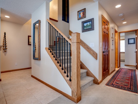 Your welcoming entrance foyer features warm wood tones, an elegant staircase, and curated artwork that sets a comfortable, homey tone the moment you arrive.